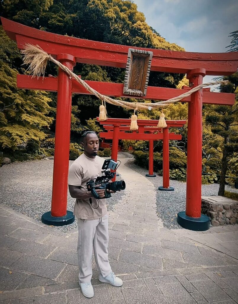Sílvio Moreira holding a camera beneath Japanese torii gates